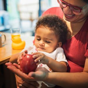 Mom letting daughter play with apple