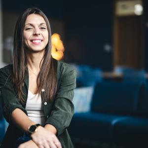 Haley Bennett sits on sofa and smiles at the camera for a portrait.